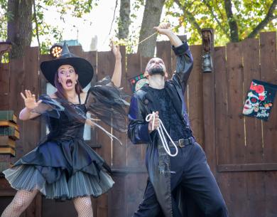 Two actors in Halloween costumes performing on an outdoor stage.