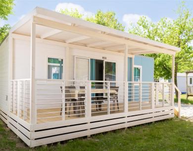 Maison mobile moderne avec véranda et chaises extérieures.