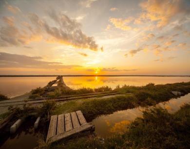 Tramonto su un lago con passerella e riflessi dorati.