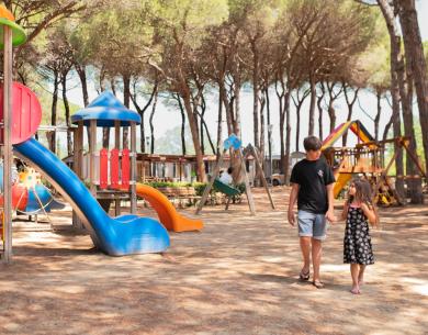 Bambini che camminano nel parco giochi sotto gli alberi.