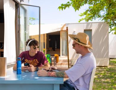 Two people sitting at an outdoor table, chatting and relaxing.