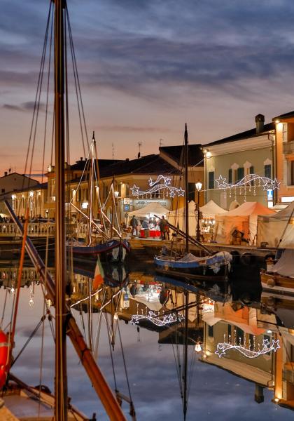 Harbor at sunset with boats and Christmas lights.