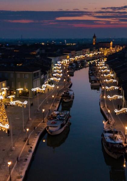 Canal lit at night with Christmas lights and moored boats.