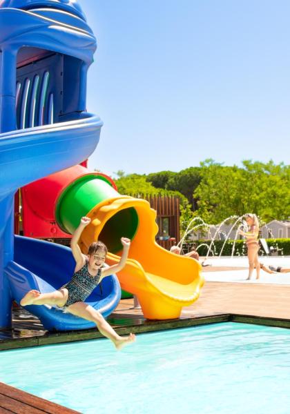 Kind genießt die Rutsche am Pool.