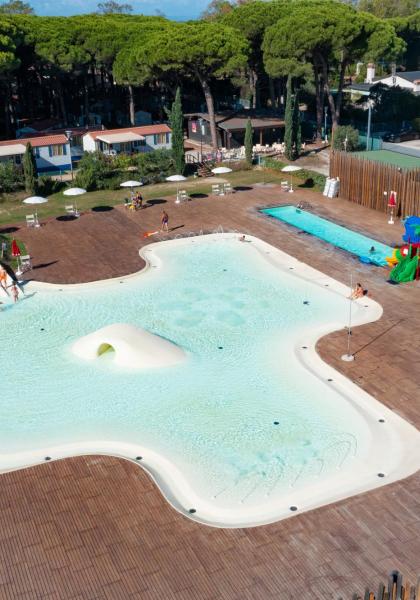 Piscine extérieure avec toboggans, parasols et aire de jeux pour enfants.