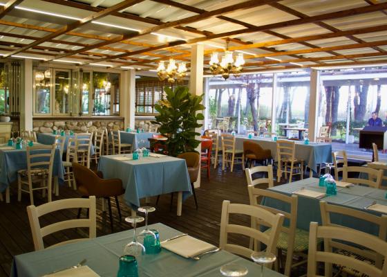 Ristorante elegante con tavoli apparecchiati, grandi finestre e vista sul giardino.