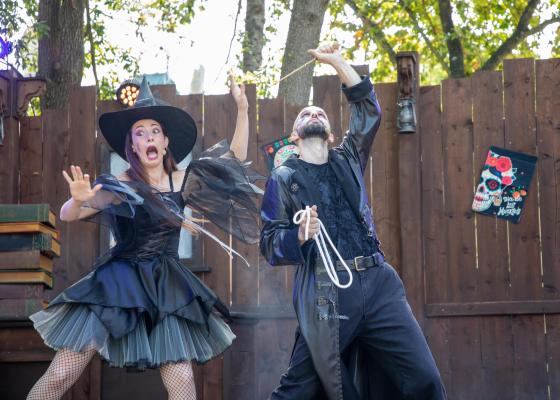 Two actors in Halloween costumes performing on an outdoor stage.