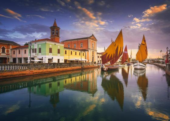 Colorful buildings and sailboats reflected in the canal water.