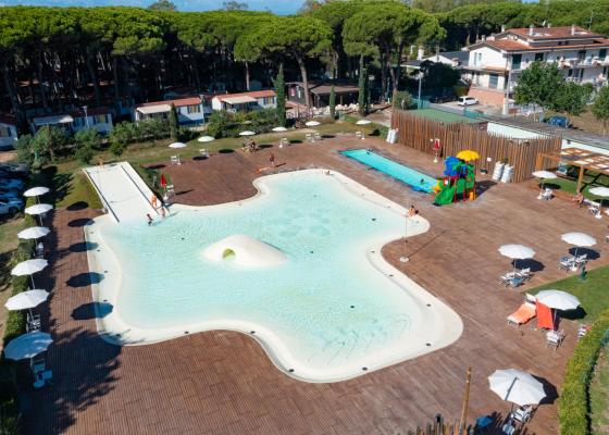 Piscina all'aperto con scivoli, ombrelloni e area giochi per bambini.