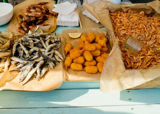 Variété de poissons frits et croquettes sur papier sulfurisé.