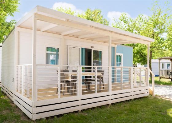 Maison mobile moderne avec véranda et chaises extérieures.