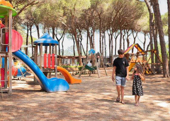 Bambini che camminano nel parco giochi sotto gli alberi.