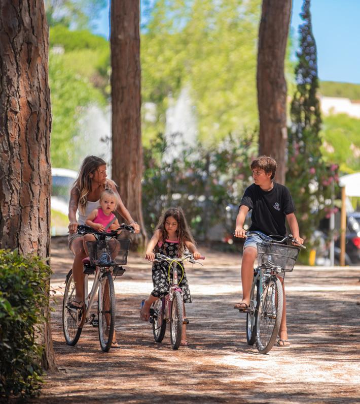 Famiglia in bicicletta su un sentiero alberato, giornata soleggiata.